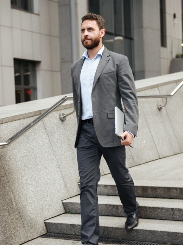 A businessperson walking with a laptop